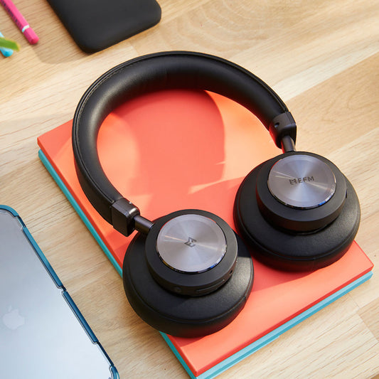 Black EFM Austin Studio Wireless Over-Ear ANC Noise Cancelling Headphones on a desk during the day